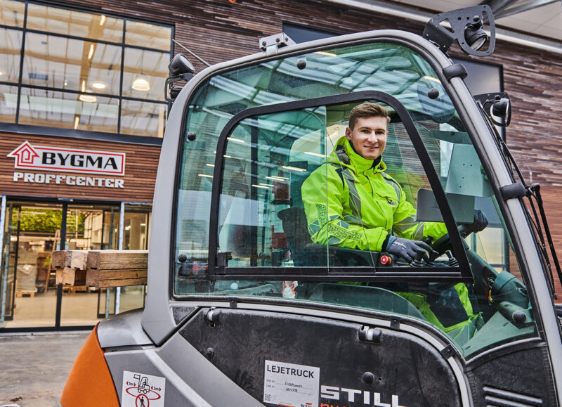 Vi Bygger Vejle: Ung mand smiler i lejetruck med træ foran Bygma.