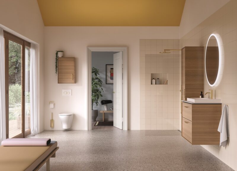 Vi Bygger Vejle: Lyst og moderne badeværelse med træmøbler, gulddetaljer, bruseniche, væghængt toilet og stort vindue.