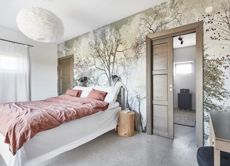 Vi Bygger Vejle: Lyst soveværelse med rosa sengetøj, træmural, fjerlampe og terrazzo-gulv.