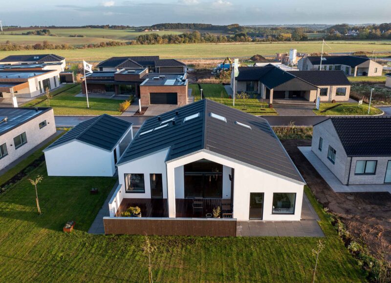Vi Bygger Vejle: Moderne parcelhuse i nybyggerområde, nogle under opførelse, med grønne marker.