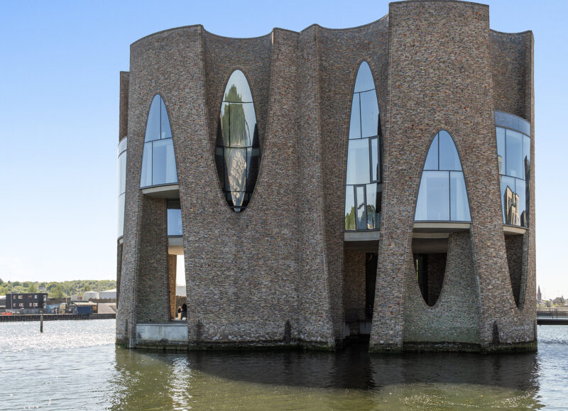Vi Bygger Vejle: Bølgen, ikonisk bølgeformet bygning af tegl med ovale vinduer, placeret i Vejles havnebassin.