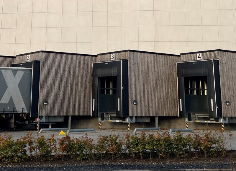 Vi Bygger Vejle: ALFIX bygning med fire træbeklædte læsseramper, en ALFIX lastbil, siloer og et Dannebrog-klistermærke.