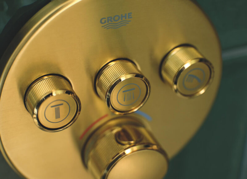Vi Bygger Vejle: Grohe brusetermostat i gylden finish med kontrolknapper for bruser, håndbruser og karbad.